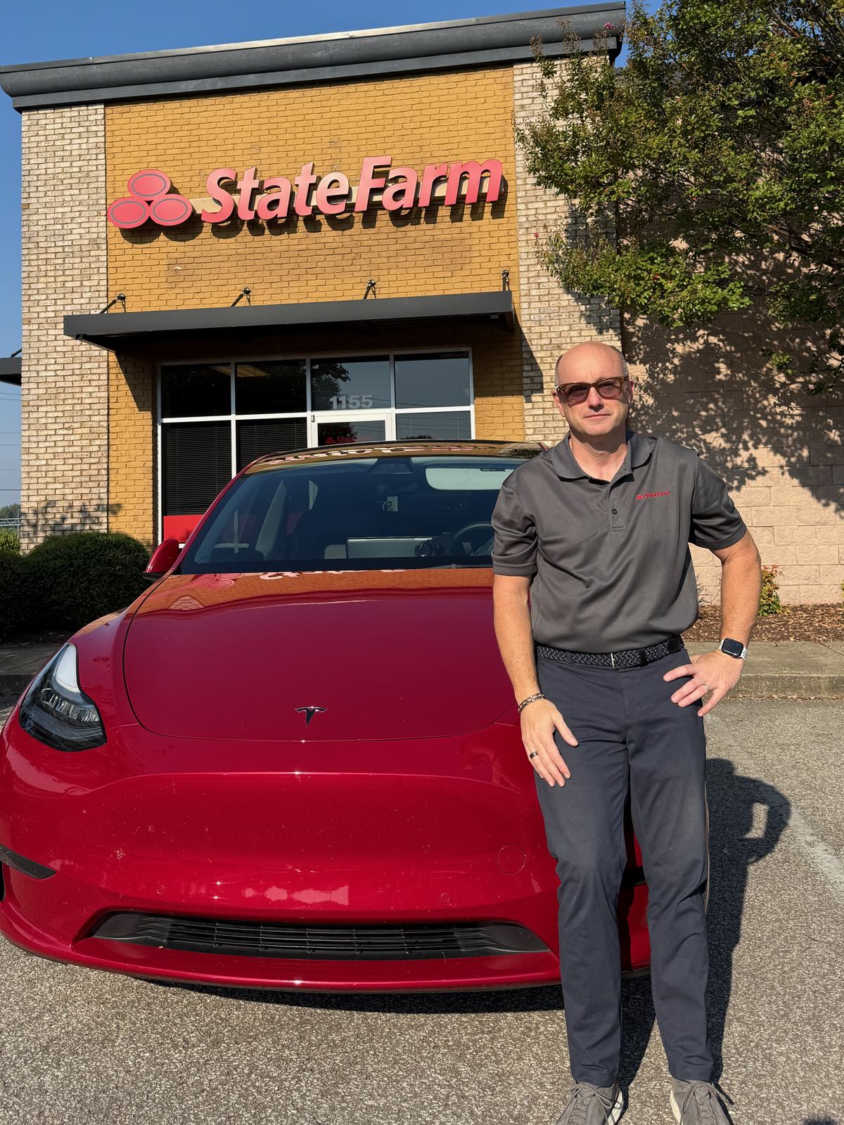Wes Harris standing beside a red Tesla outside his Jackson, Tennessee insurance office